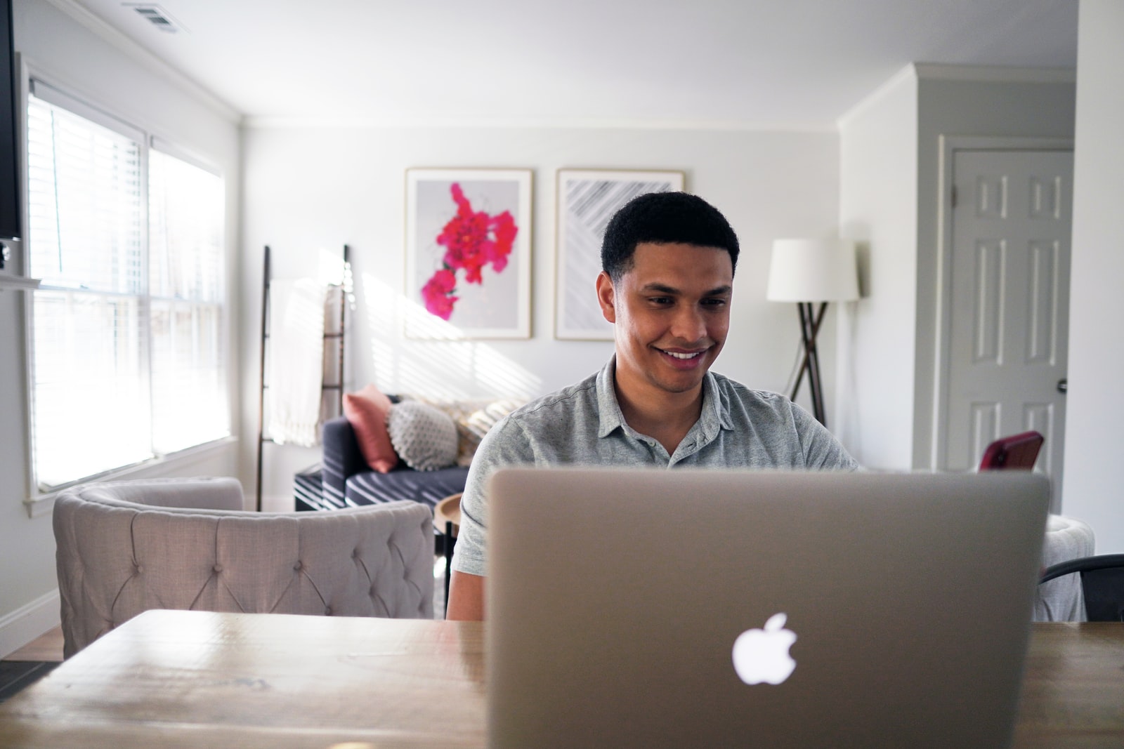 man in gray hoodie sitting on chair in front of silver macbook